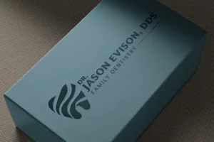 DR. Jason Evison logo printed on a blue box and lit in a dark room.