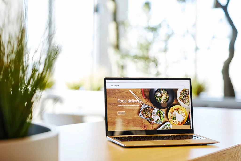 Laptop on a table displaying a food delivery website, representing modern website design and online ordering.