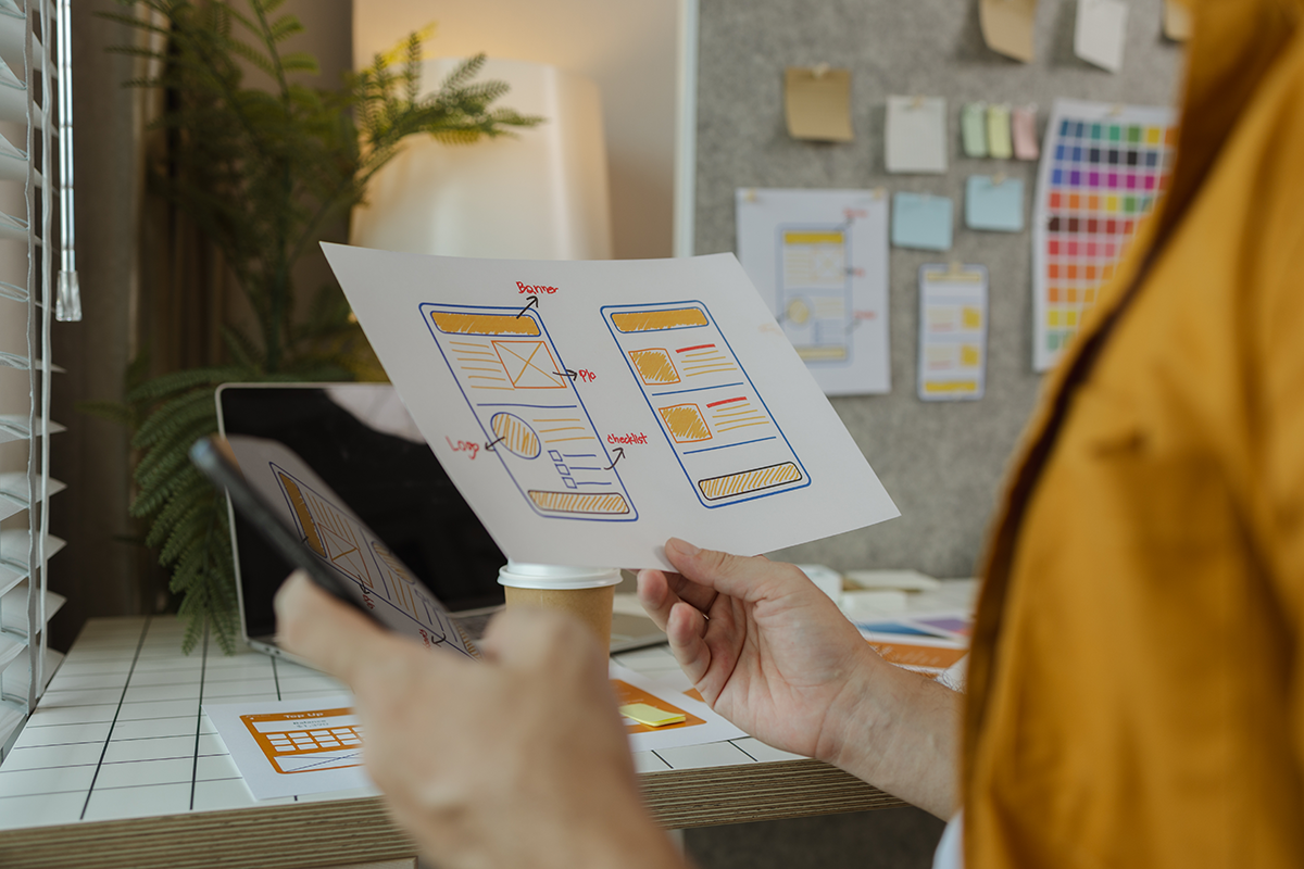 Designer reviewing mobile app wireframes and UI layouts in a creative workspace
