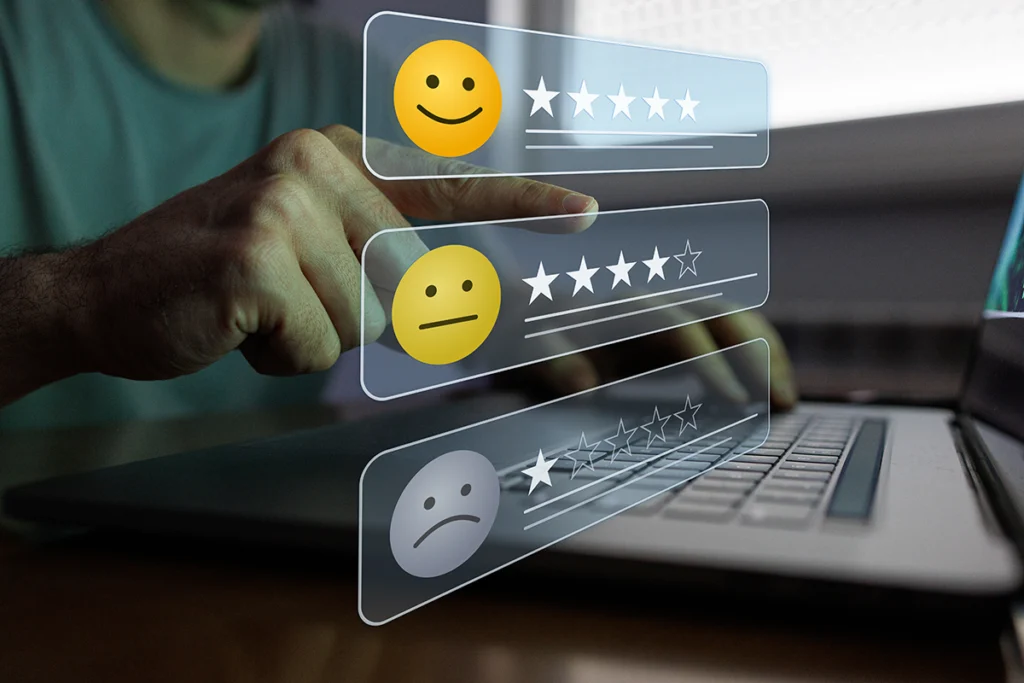 A hand selects a customer satisfaction rating panel with smiley faces and star reviews on a laptop screen.