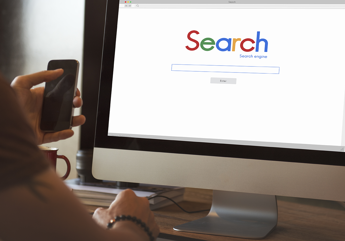Person using a desktop computer displaying a simple search engine homepage with a large search box.